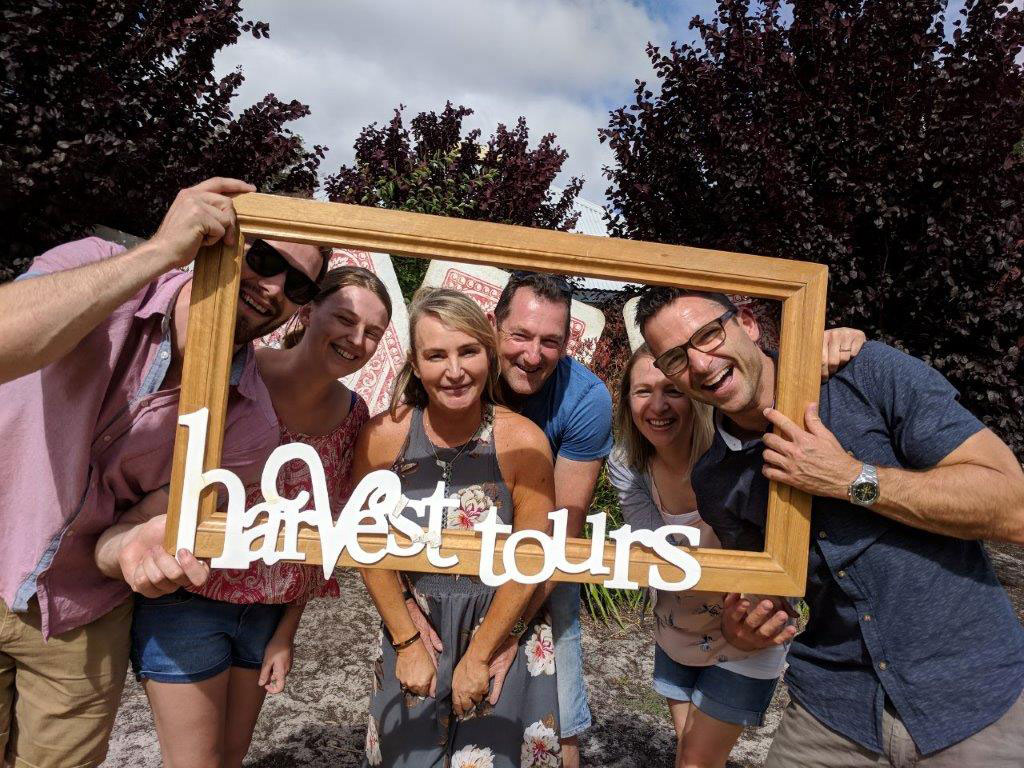 A family on a Margaret River tour holding a Harvest Tour logo