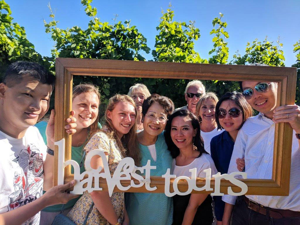 A group at the vineyard holding Harvest Tour logo